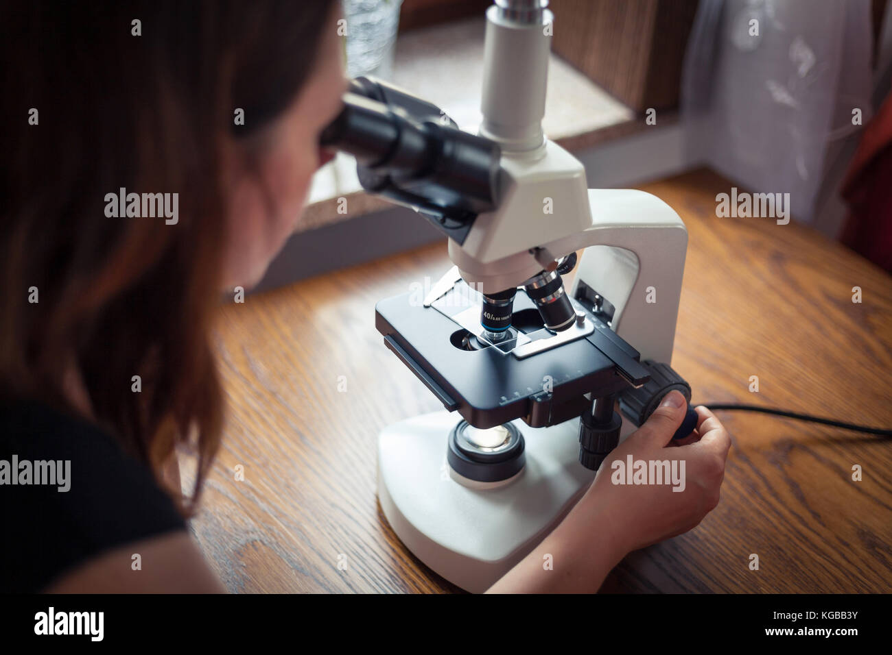 Frau durch Mikroskop zu Hause suchen Stockfoto