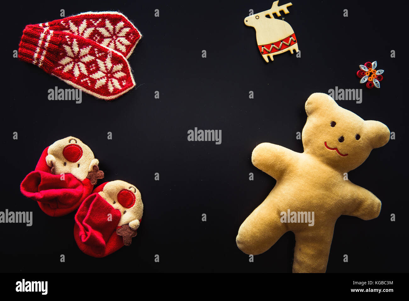 Baby Handschuhe, Stiefeletten und ein Teddybär auf Schwarz Stockfoto
