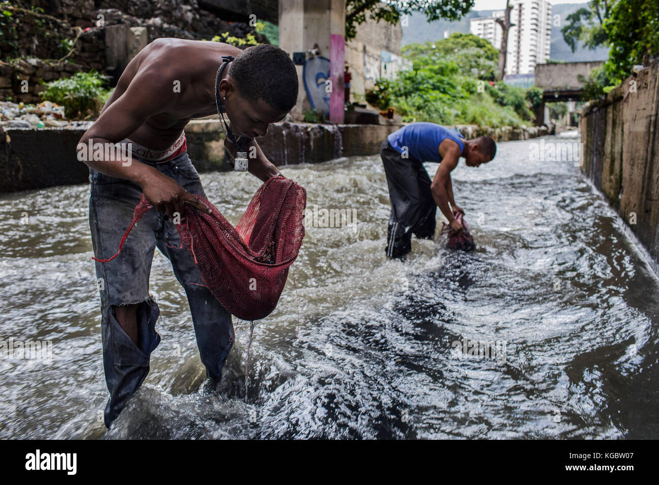 Caracas, Venezuela. Juni 2017. Augusto Rengil und Tomas Melo suchen im Wasser des Flusses Guaire, dem offenen Hauptwasserkanal in Caracas, Venezuela, nach wertvollen Objekten, 25. Juni 2017. Tag für Tag versuchen sie, ihren Lebensunterhalt in den stinkenden Kaiserspulen zu verdienen. Quelle: JM López/dpa/Alamy Live News Stockfoto