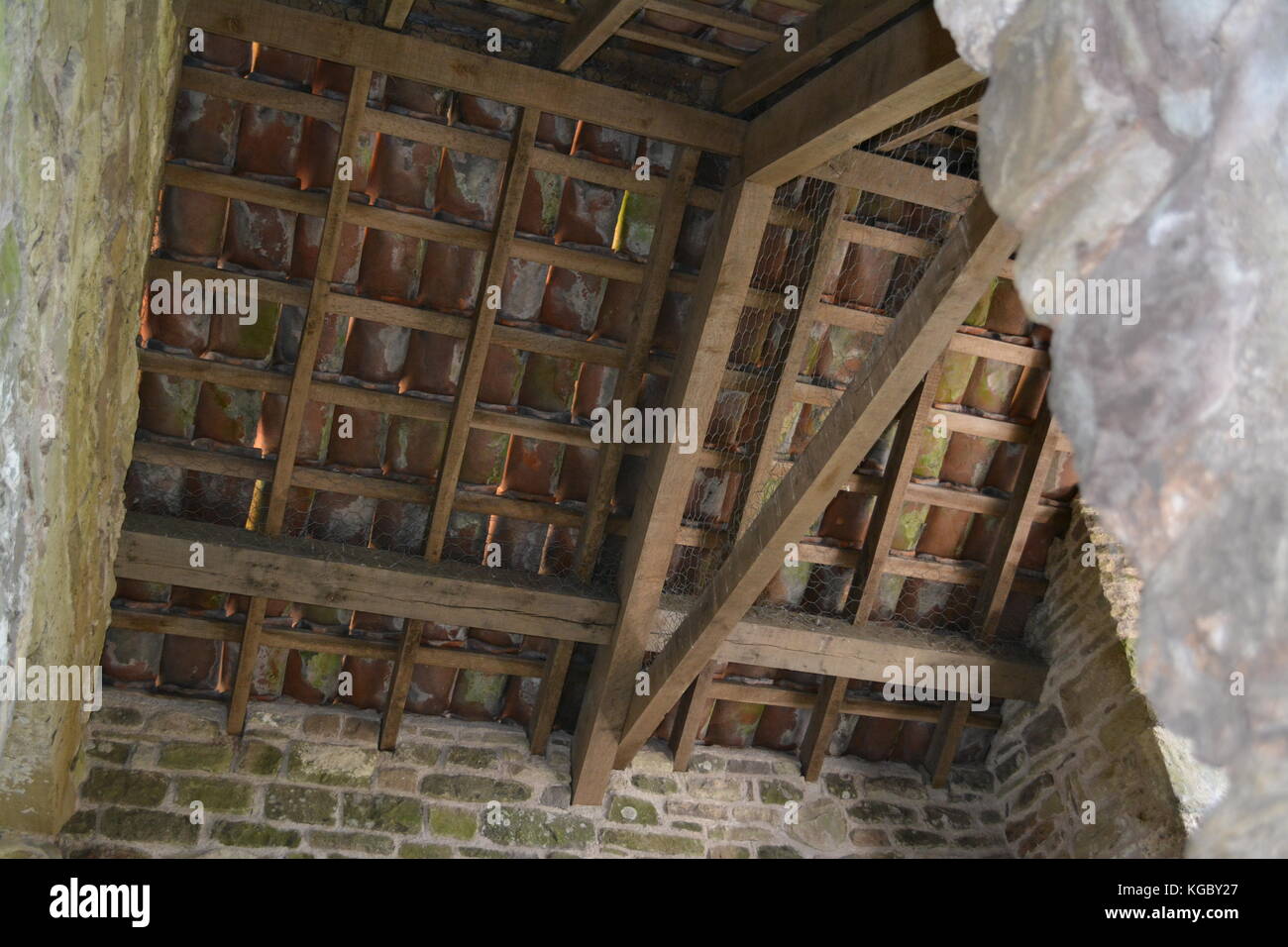 Holz holz dach Detail mit Tonziegeln, die über die von Steinmauern auf Teil des antiken Gebäudes re Erbe und Bewahrung unterstützt. Stockfoto