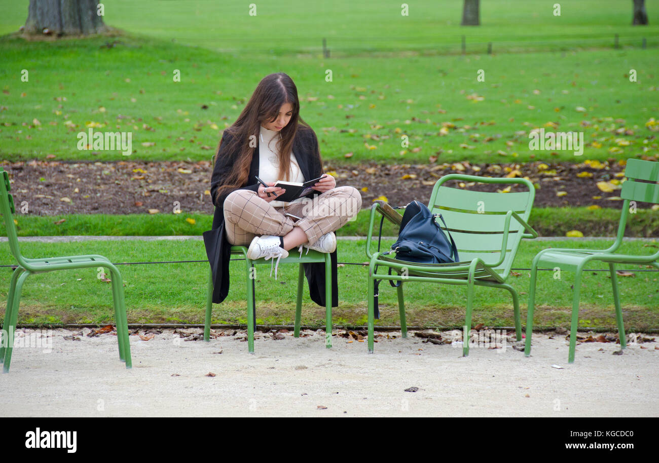 Paris, Frankreich. Jardin des Tuileries, junge Frau, die in einem Notizbuch / Tagebuch schreibt Stockfoto