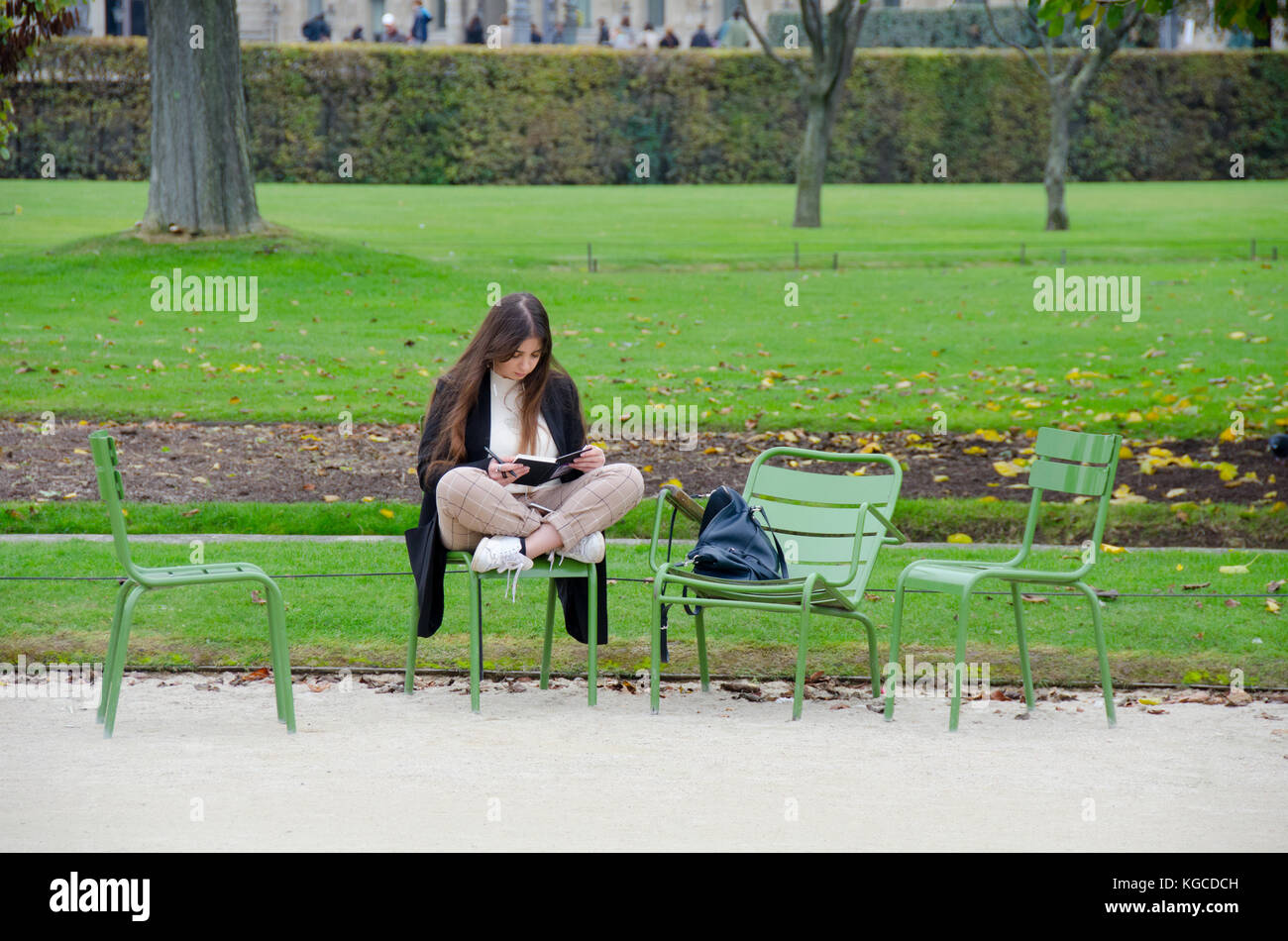 Paris, Frankreich. Jardin des Tuileries, junge Frau, die in einem Notizbuch / Tagebuch schreibt Stockfoto