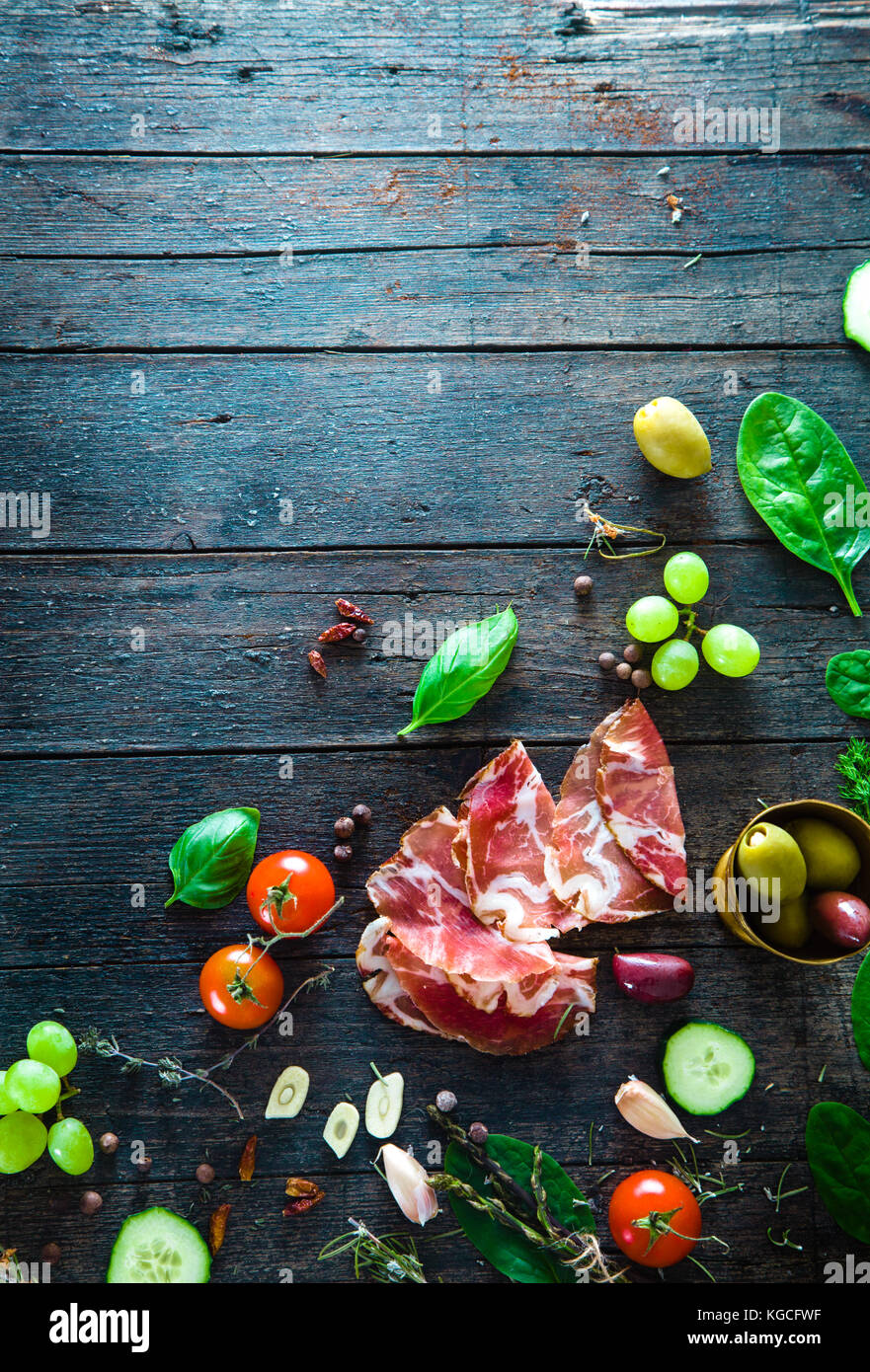 Italienischer Schinken, Prosciutto und Salami. Zutaten für Bruschette, Crostini oder Sandwich Bar. rustikale Blick von oben auf die Zutaten. Schinken mit Gemüse und spic Stockfoto