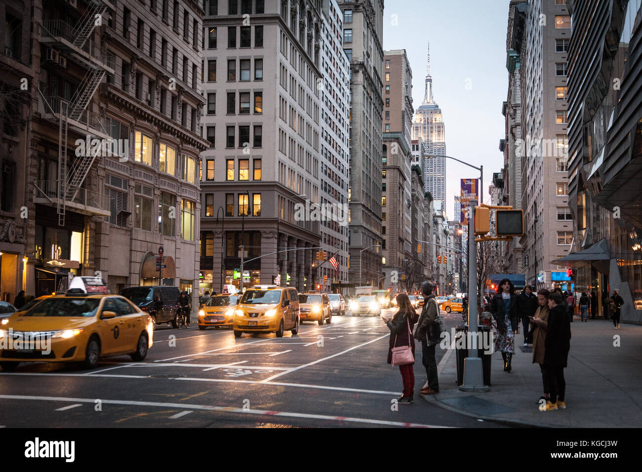 Midtown Manhattan am Abend, den 19. März 2016. Die Menschen warten, die Straße zu überqueren, wie Yellow Cabs Antrieb durch. Stockfoto