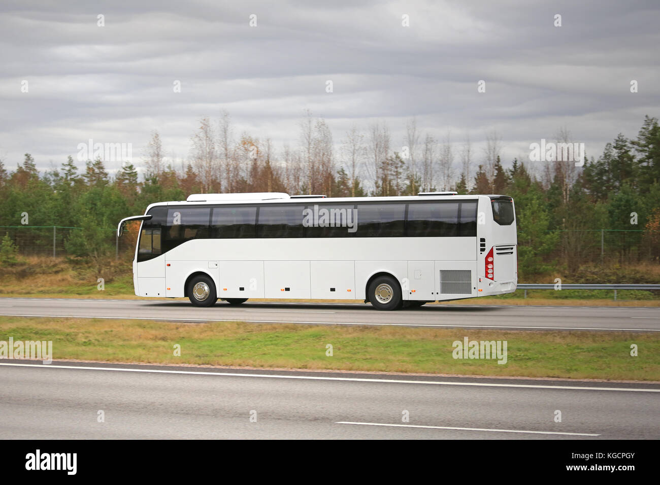 Die neuen weißen Coach Bus bewegt sich entlang der Autobahn an einem bewölkten Herbst Tag. Stockfoto