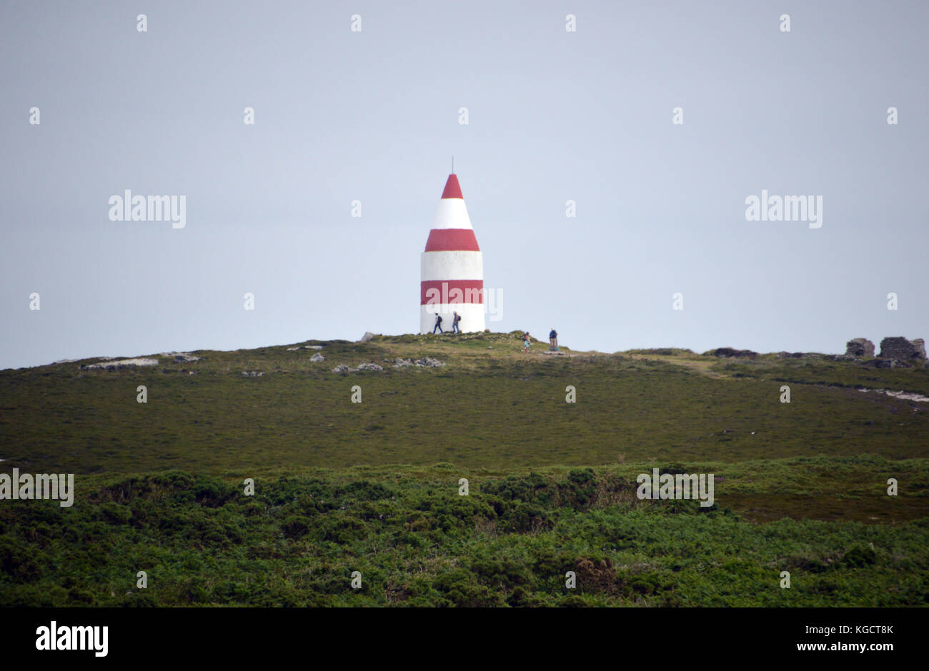 Wanderer rund um den trig Point und die rot-weiße Tag - Markierung auf St Martins Kopf, Isles of Scilly, Vereinigtes Königreich. Stockfoto