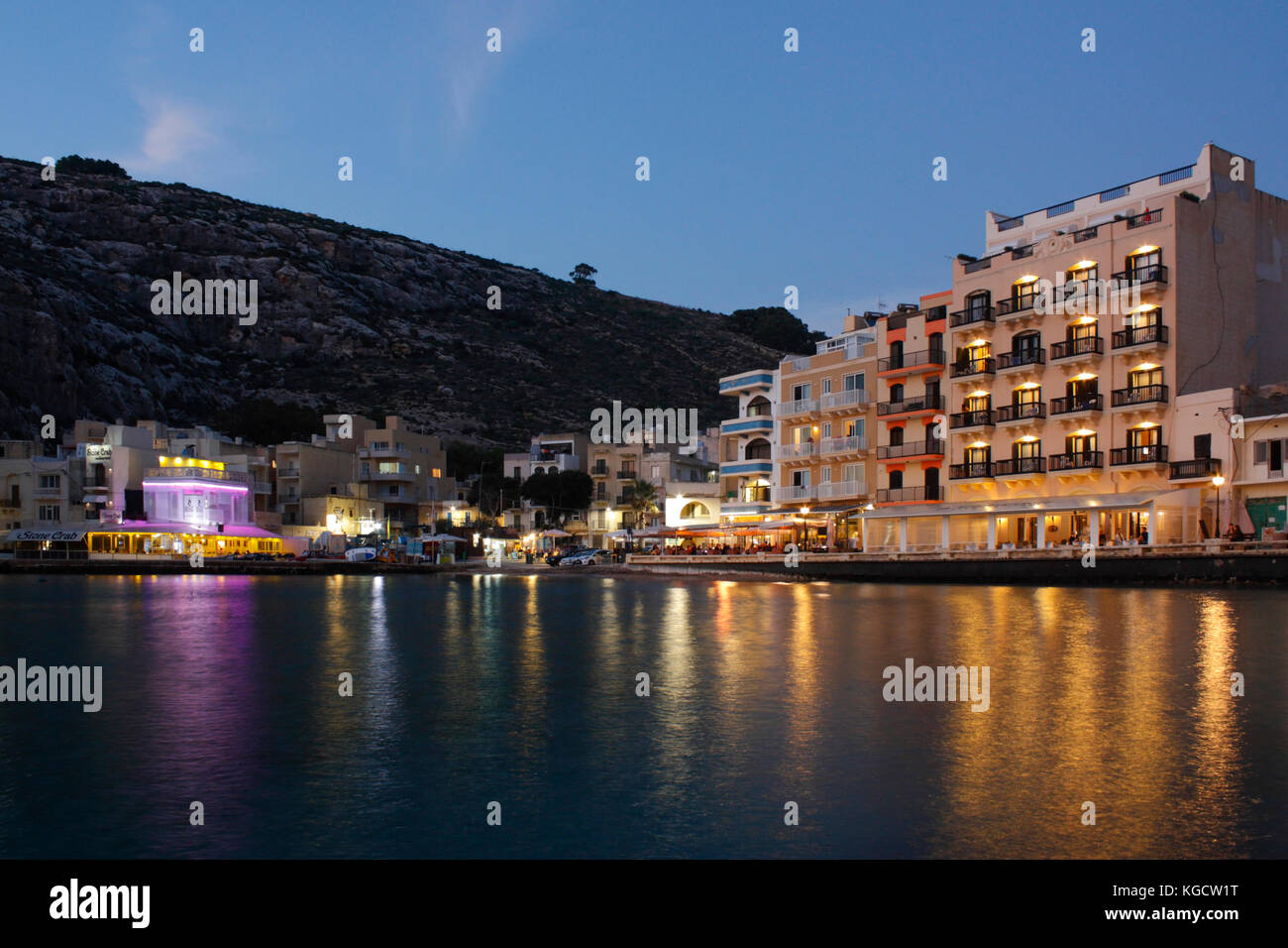 Der Küstenort Xlendi (ausgesprochen Shlendy) in Gozo, Malta, in der Dämmerung, mit Hotels und Restaurants beleuchtet. Tourismus im Mittelmeerraum. Stockfoto