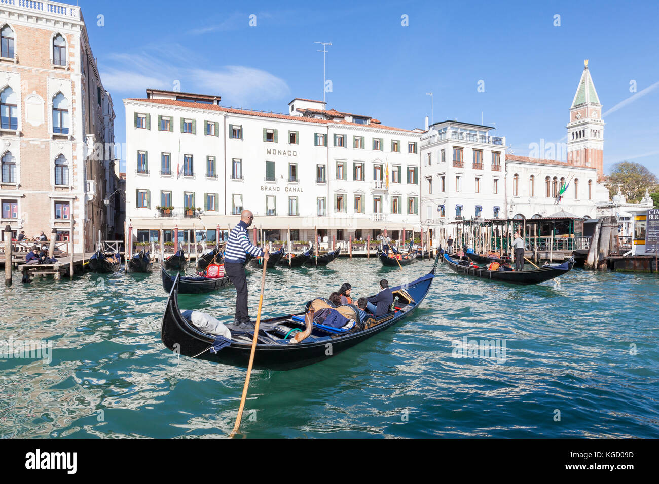 Gondeln mit Touristen auf dem Canal Grande, Venedig, Italien, Schlange, um ihren Kunden im San Marco zu verlagern. Schließen Sie bis zu drei Viertel der hinteren Winkel auf einem gehen Stockfoto