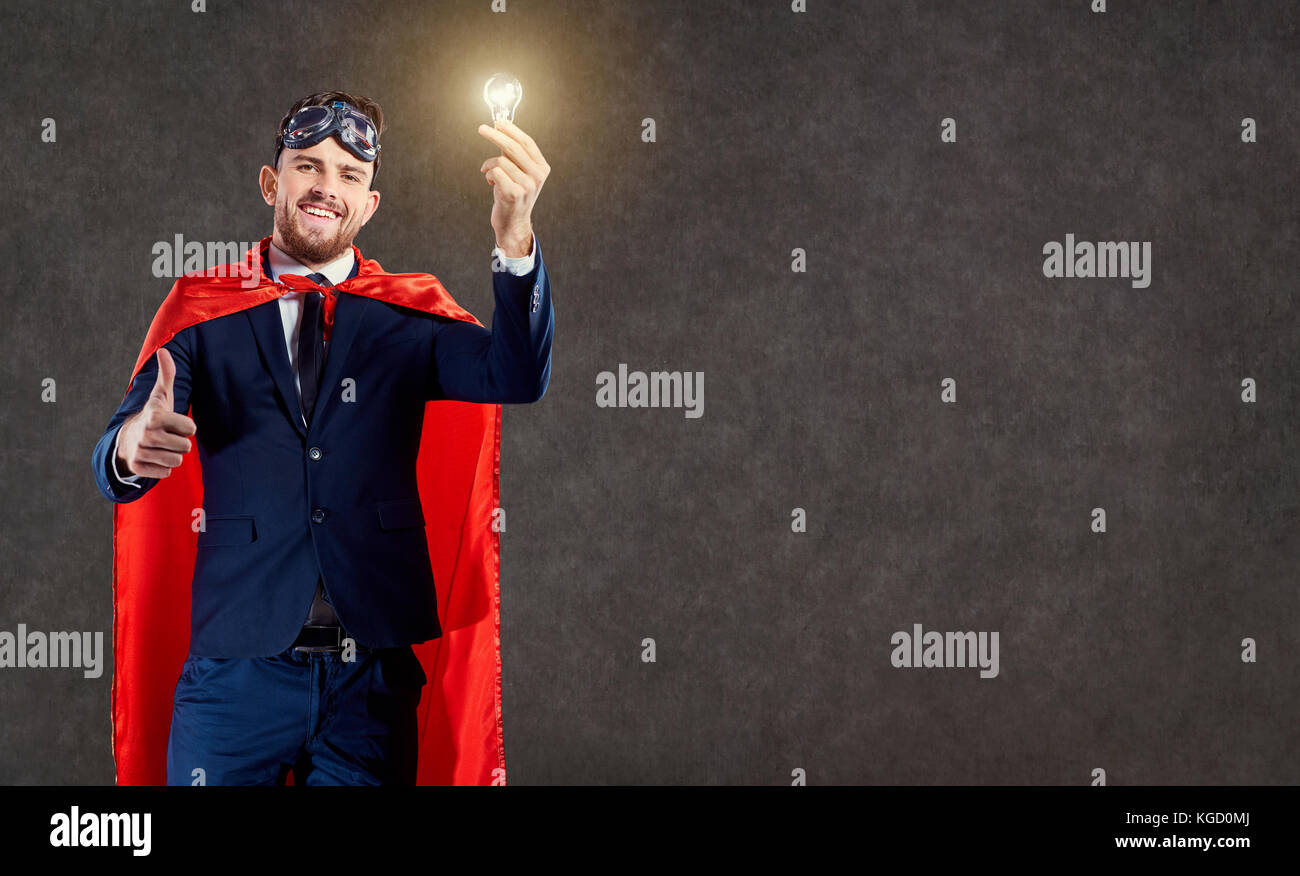 Ein Geschäftsmann in einen Superhelden Kostüm mit einem leuchtenden  Glühbirne in der Hand Stockfotografie - Alamy
