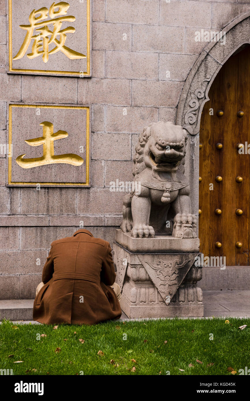 Ein Mann ist in Gedanken versunken vor einem Tempel mit seinen Kopf sitzen. Stockfoto
