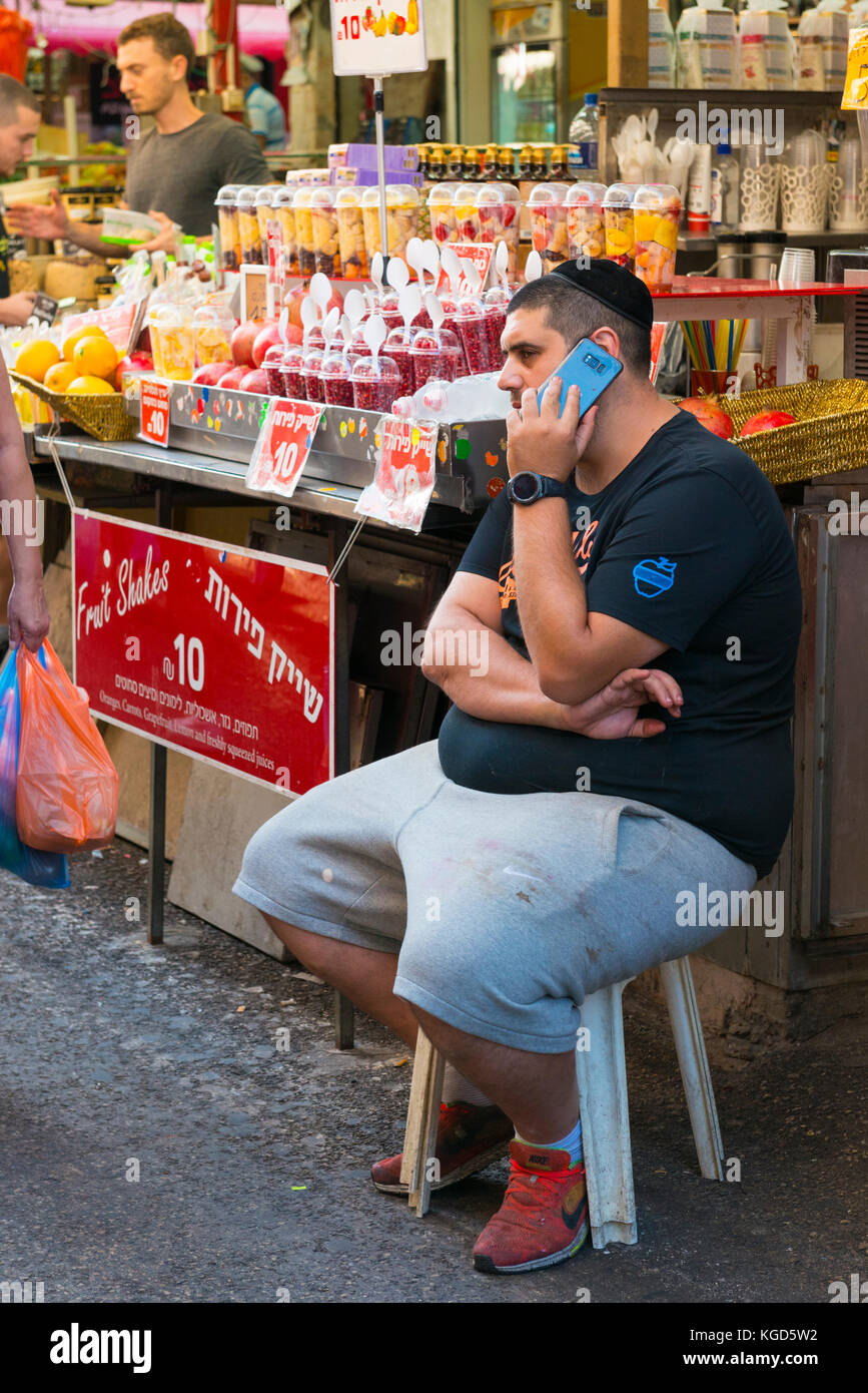 Israel das Heilige Land Tel Aviv Jaffa Jaffa Carmel Markt frisches Obst schüttelt Anbieter Fett fettleibig sitzen Barhocker Schädelkappe kippa Abschaltdruck Stockfoto