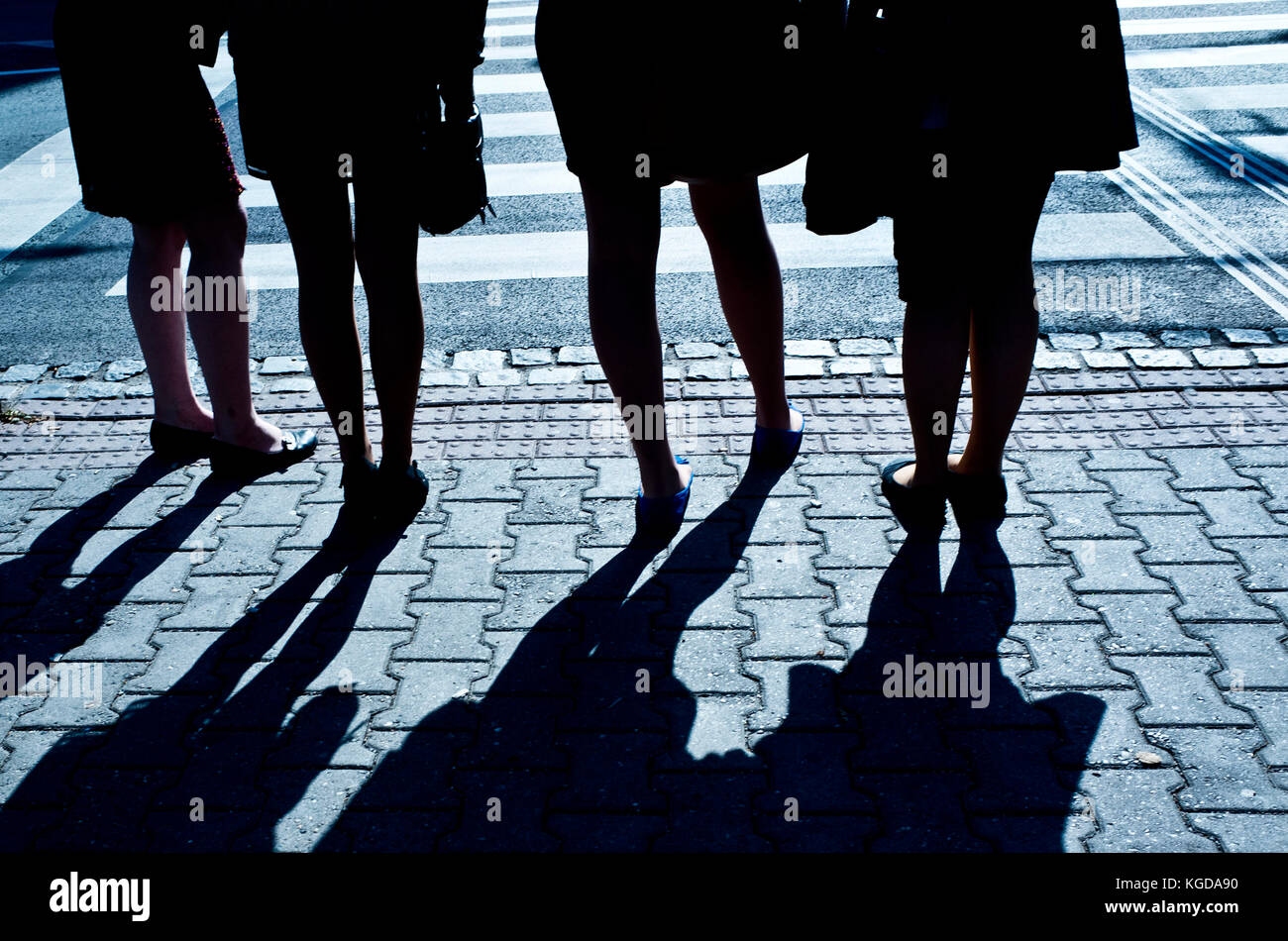 Beine von vier Frauen stehen und lange Schatten Stockfoto