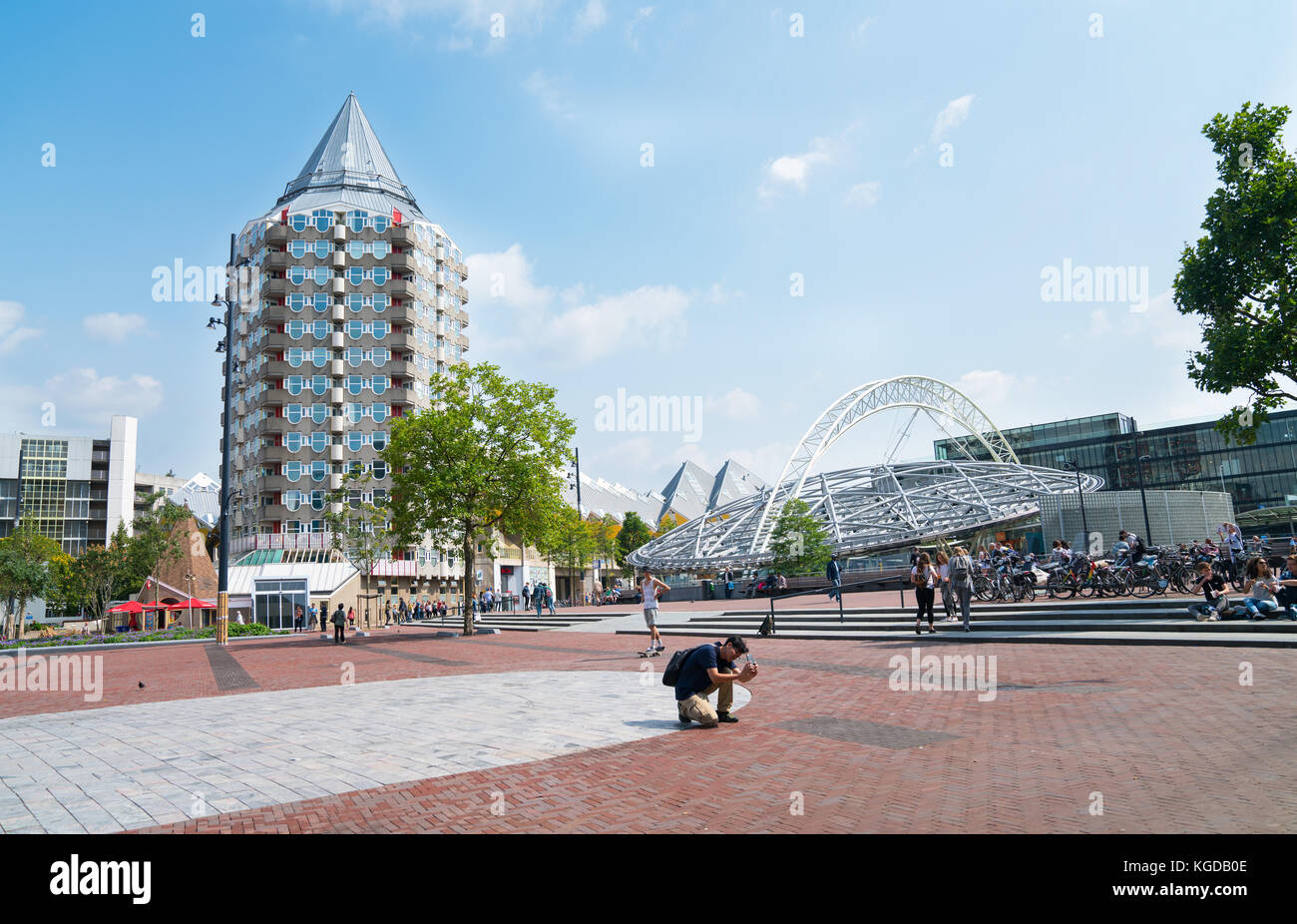 Rotterdam, Niederlande - 22 August, 2017; Mann kniet Foto vor Bild zu nehmen, während Menschen zu Fuß über blaak Square Gegend, umgeben von einer Sammlung Stockfoto