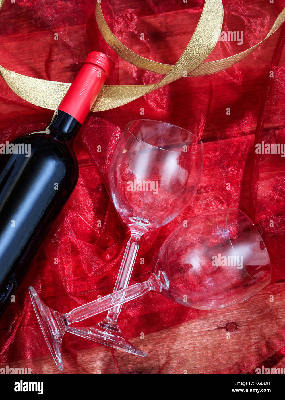 Valentines Tag Konzept. Rotwein Flasche und Gläser auf Rot Textil Stockfoto