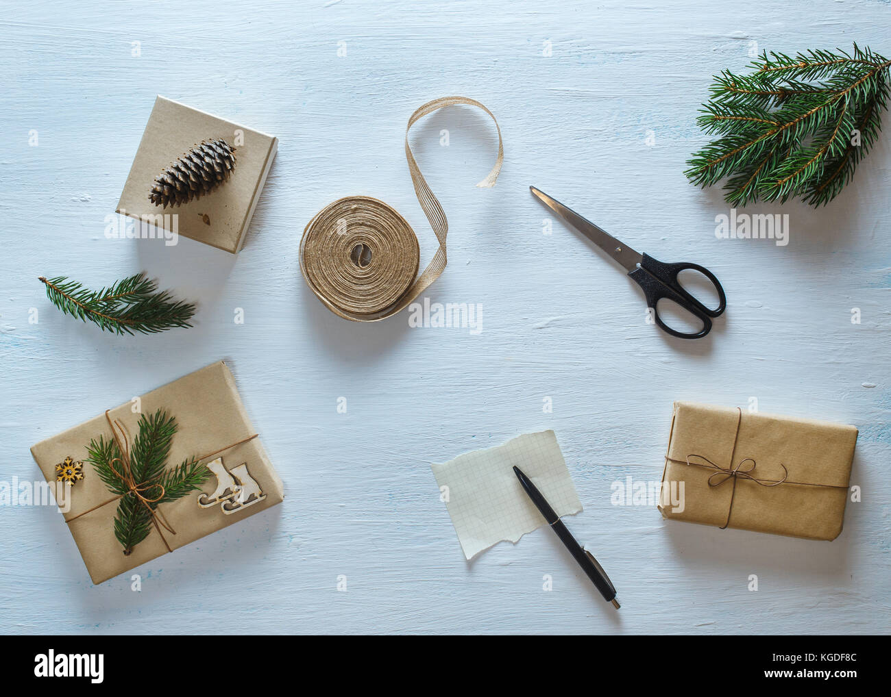 Weihnachten Geschenk Verpackungen Zusammensetzung. Weihnachten Geschenke, tannenzweigen, Schere, Band, Stift mit leeren Blatt auf Blau Schreibtisch. Flach, Ansicht von oben Stockfoto