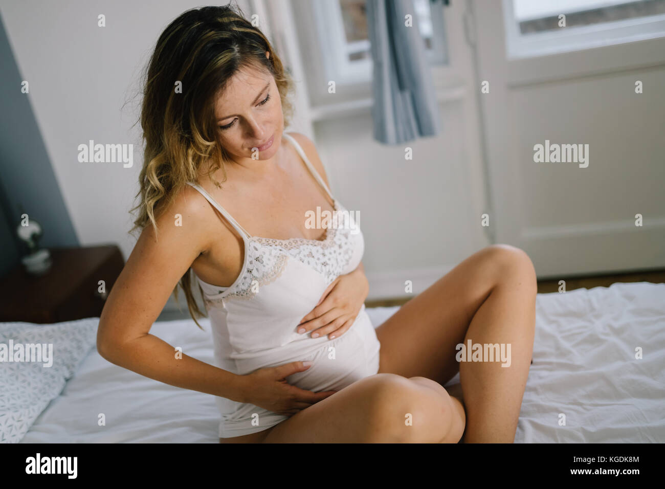 Portrait von attraktiven schwangere Frau saß auf dem Bett Stockfoto
