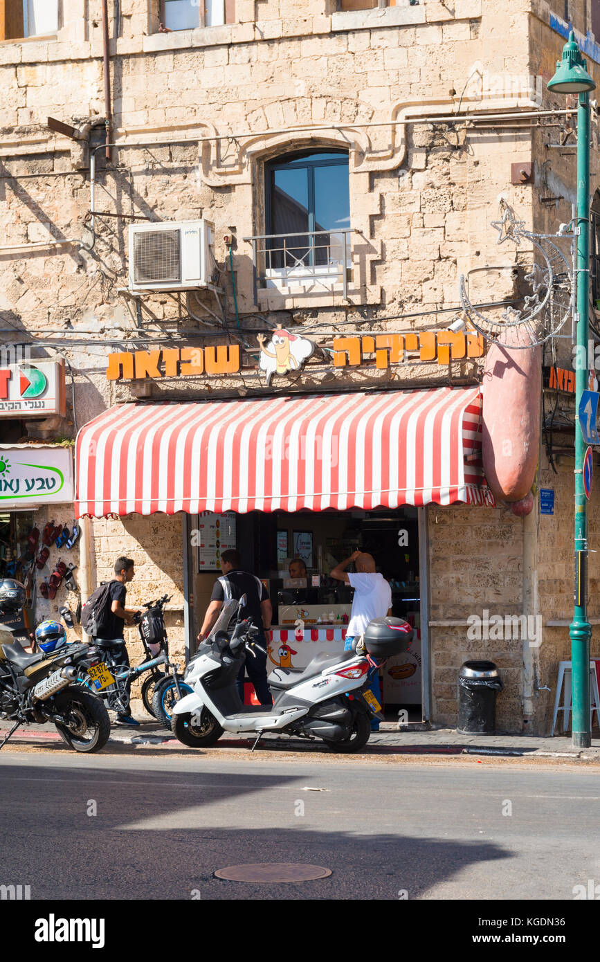 Israel das Heilige Land Tel Aviv Jaffa Yofa Straße Ecke hot dog Shop Shop fast food Snack bar Cafe Rot Weiß blind Vordach scooter Fahrrad Fahrräder Stockfoto