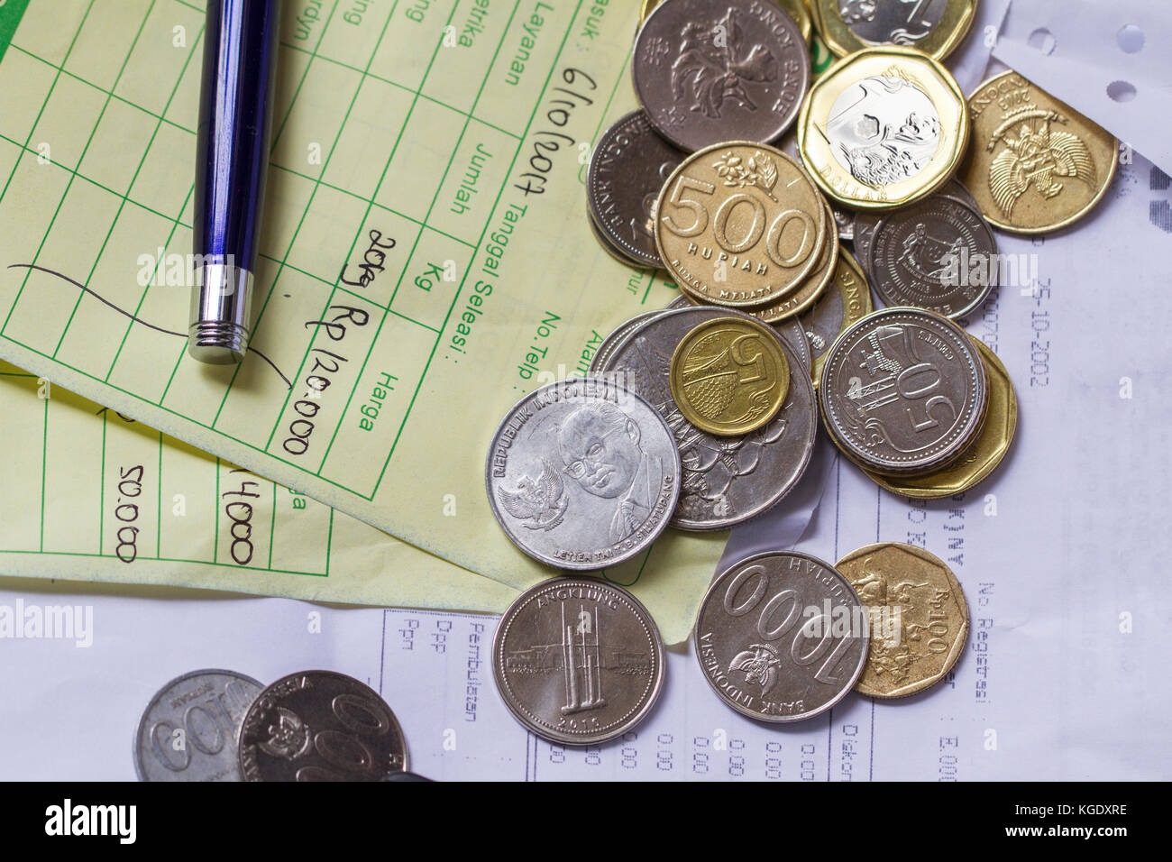 Draufsicht/flache Anordnung des artikels zur Berechnung des Zahlungsbelegs mit indonesischer Rupiah, Singapur-Dollar-Münzen und handschriftlichen Rechnungen Stockfoto