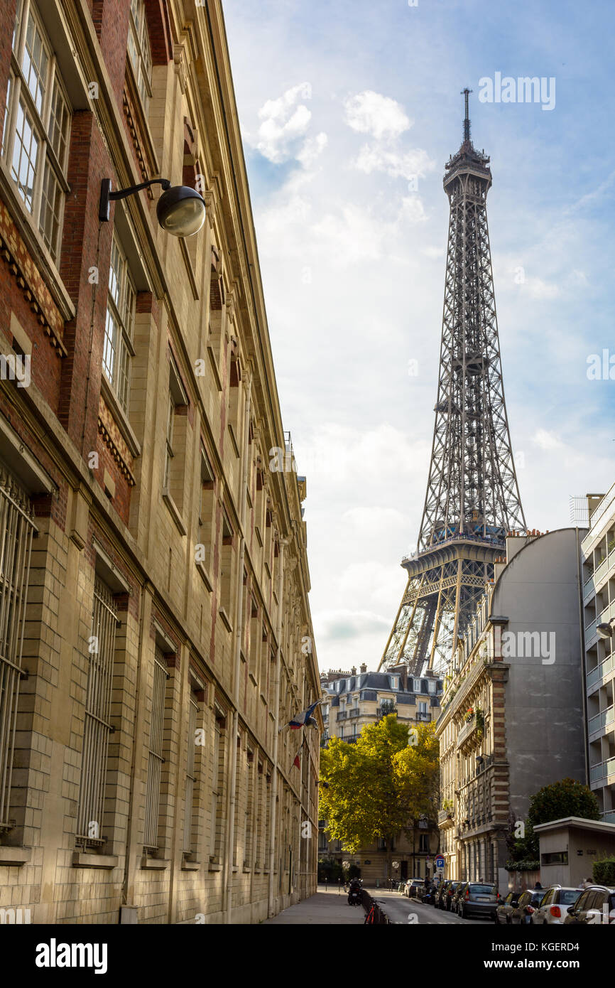 Ansicht aus einer Seitenstraße der majestätischen Eiffelturm in ihrer unmittelbaren Nachbarschaft mit den typischen Pariser Gebäude im Vordergrund. Stockfoto