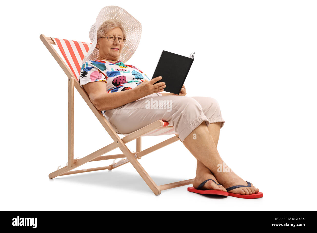 Ältere Frau im Liegestuhl sitzen und lesen ein Buch auf weißem Hintergrund Stockfoto