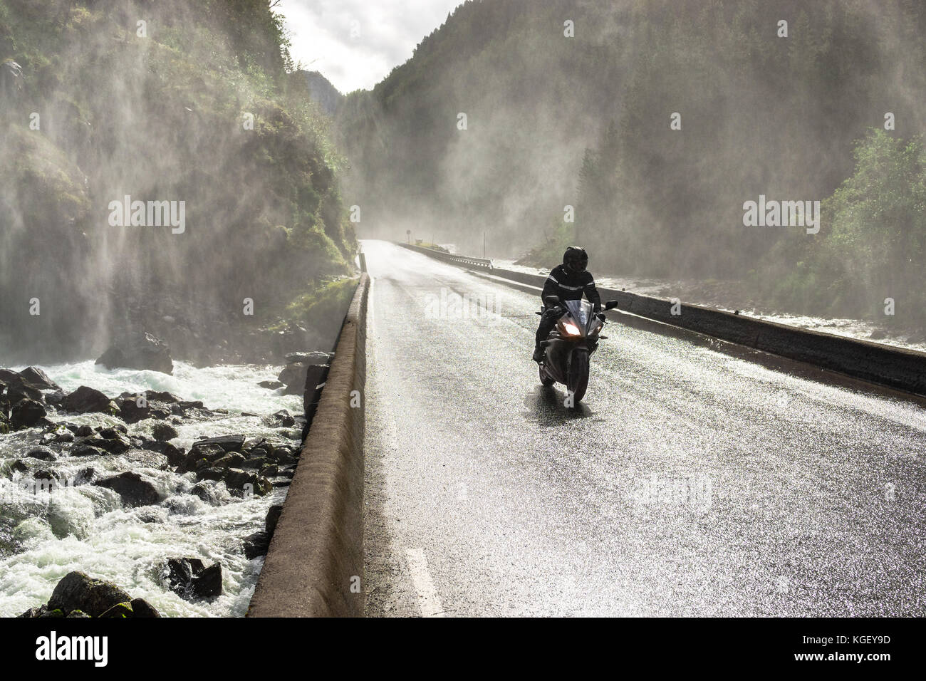 Motorrad schneller Fahrt auf nassen Canyon Valley Road und der Brücke über den Fluss. Stockfoto