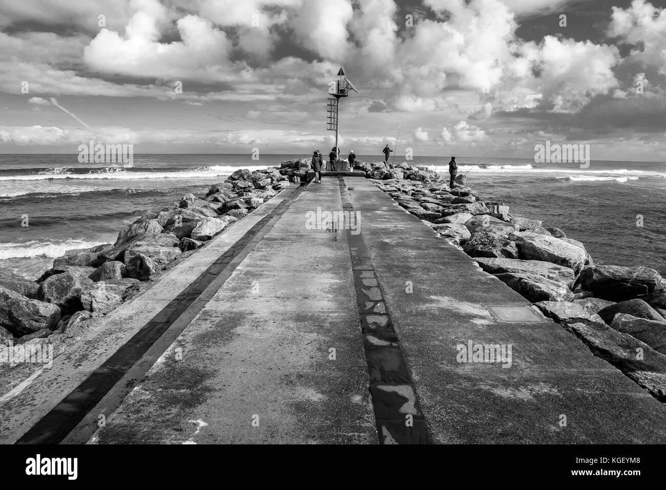 Eine weit entfernte Gruppe von Leuten auf einem Pier an einem bewölkten Tag Stockfoto