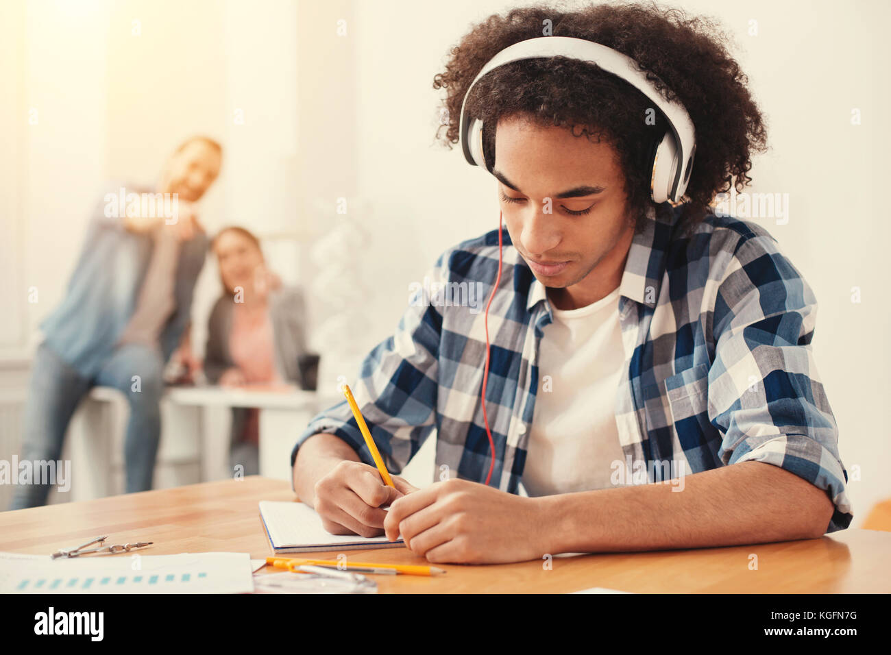 Konzentriert student Musik hören und sich Notizen Stockfoto