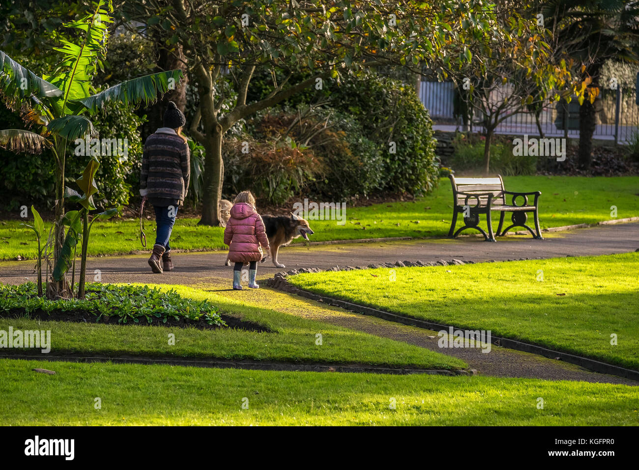 Eine Mutter und Tochter, die einen Hund in einem Park spazieren gehen. Stockfoto