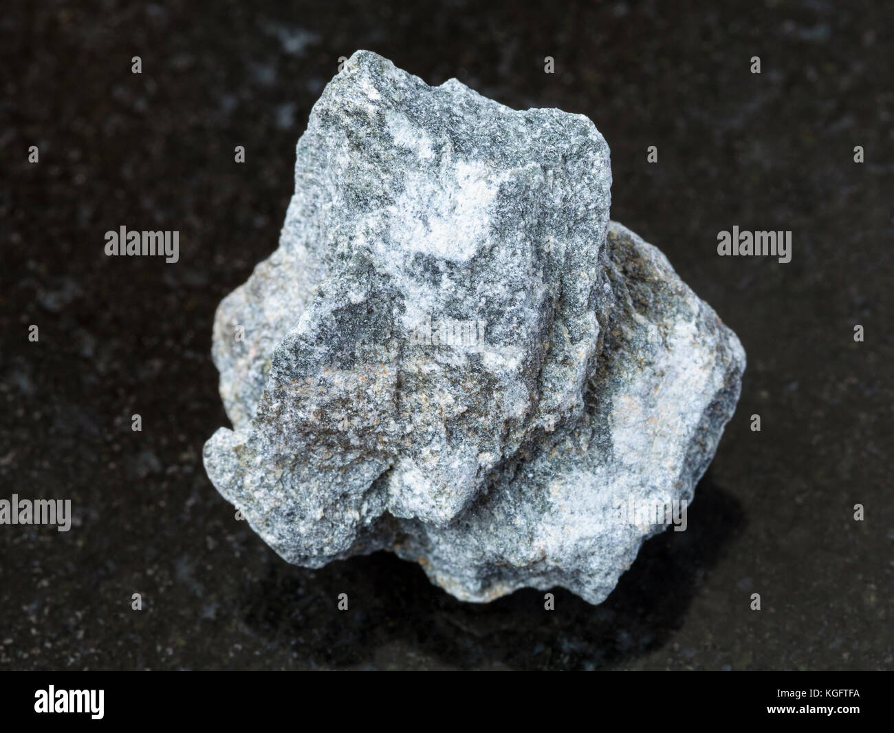 Makroaufnahmen von natürlichen Mineralgestein Muster - Rohstoff Speckstein Stein (talkum - Schiefer) auf dunklem Granit Hintergrund Stockfoto