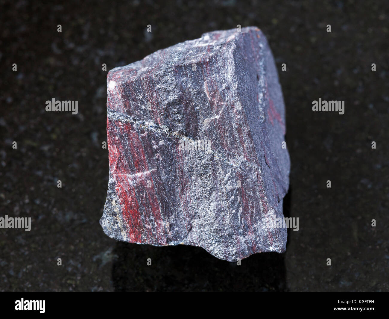Makroaufnahmen von natürlichen Mineralgestein Muster - Grobe jaspilite (eisenhaltiges Quarzit) Stein auf dunklem Granit Hintergrund Stockfoto