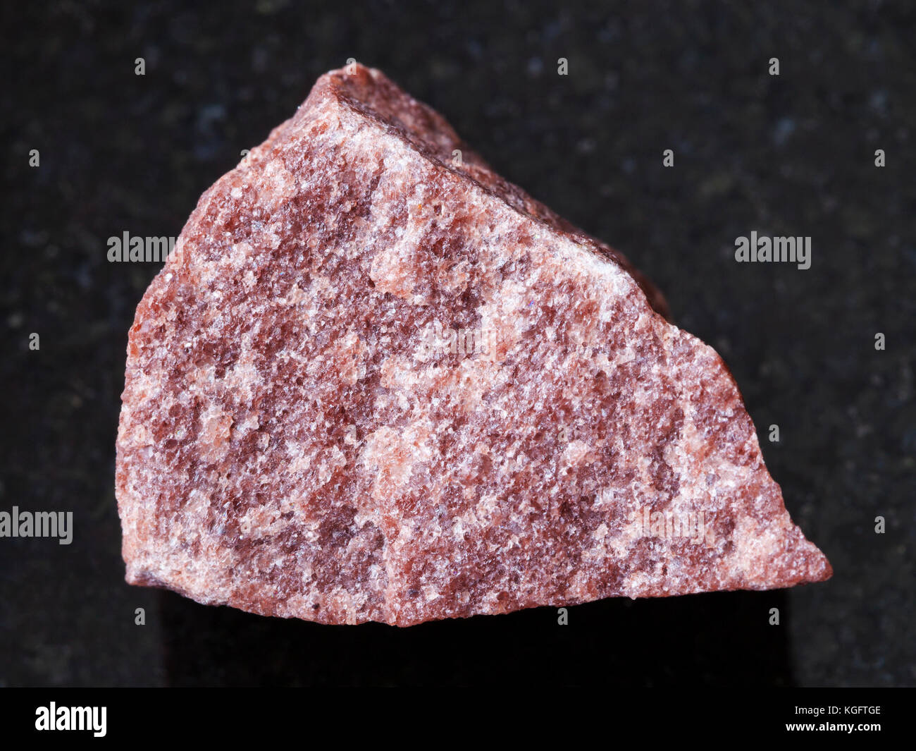 Makroaufnahmen von natürlichen Mineralgestein Muster - grobe rosa Quarzit Stein auf dunklem Granit Hintergrund Stockfoto