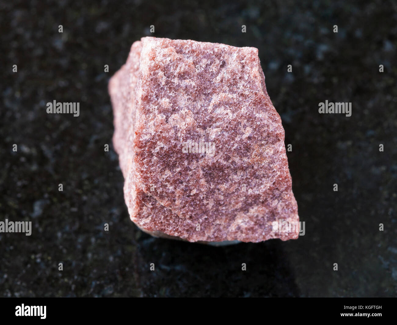 Makroaufnahmen von natürlichen Mineralgestein Muster - Roh rosa Quarzit Stein auf dunklem Granit Hintergrund Stockfoto