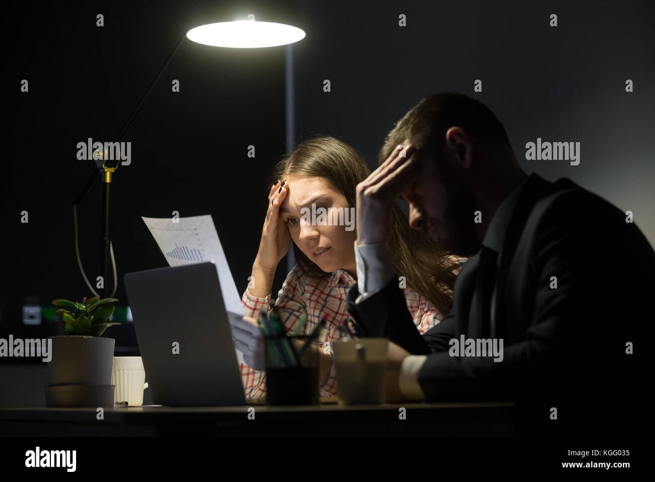 Zwei Kollegen in schlechter Gesellschaft Bericht am späten Abend treffen. Mann und Frau ihre Köpfe in den Händen halten, in Seenot. business Disaster anhand von quantitativen Simulatio Stockfoto