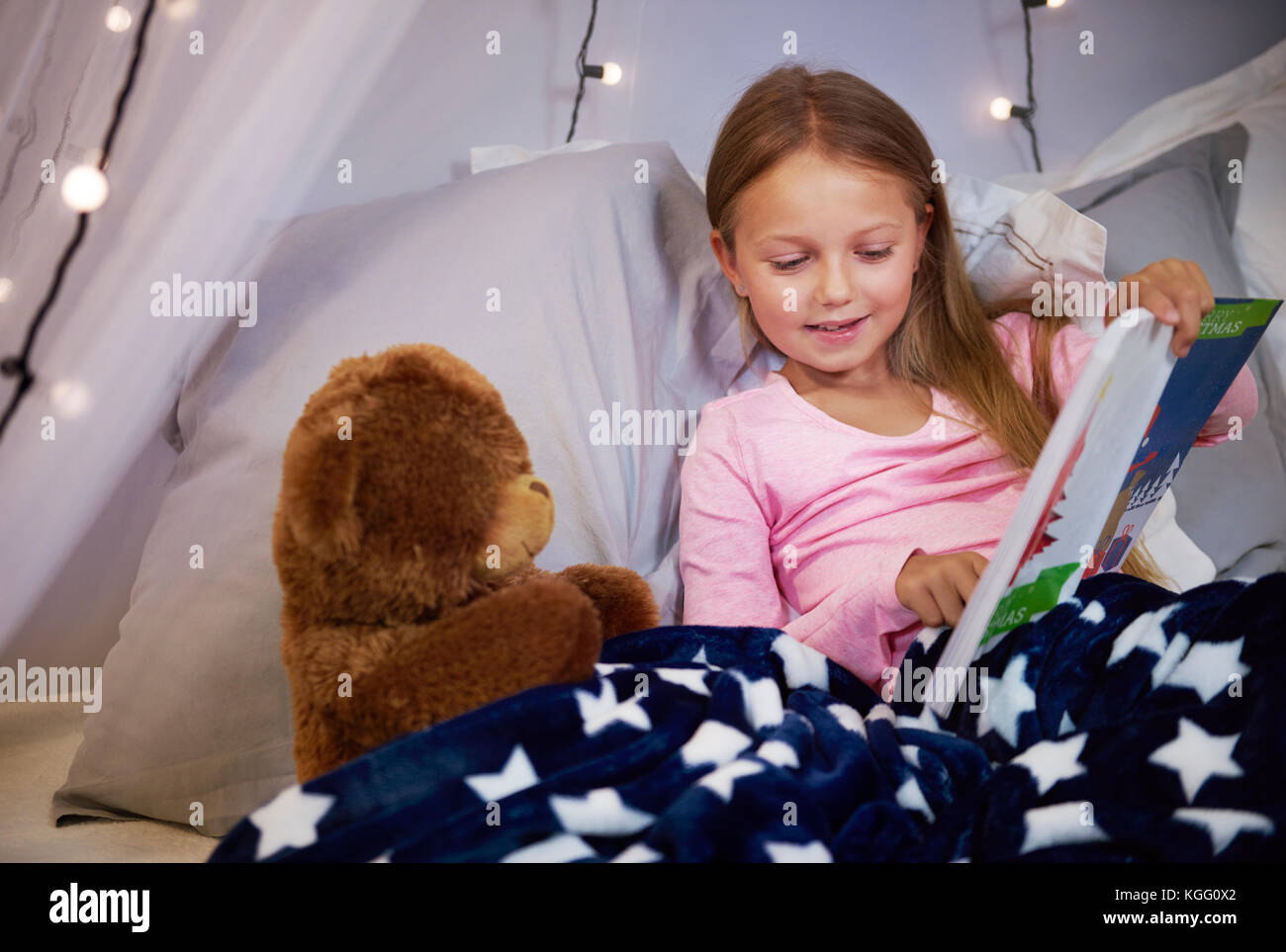 Mädchen beobachten ein Bilderbuch mit einem Teddybär Stockfoto