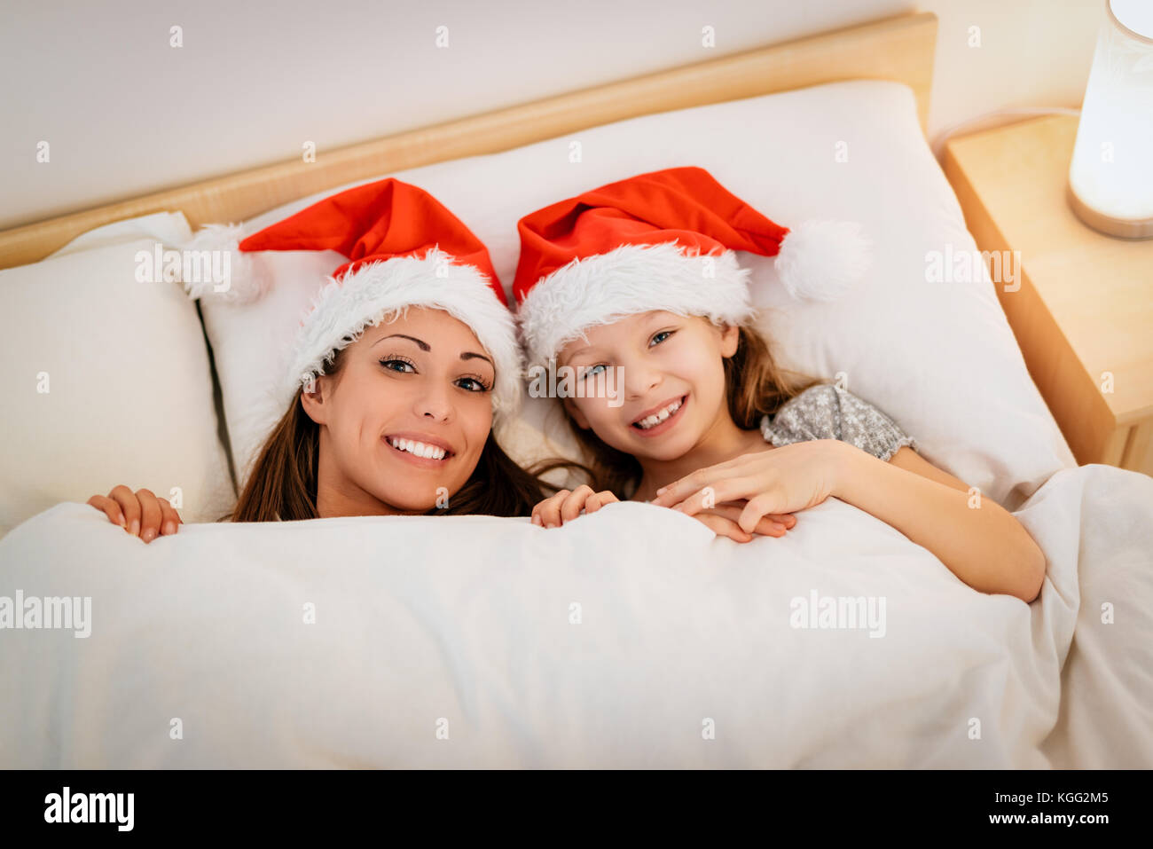 Junge Mutter mit ihrer Tochter mit Decke und genießen Sie im Bett am Weihnachtsabend, Warten auf den Weihnachtsmann. Stockfoto