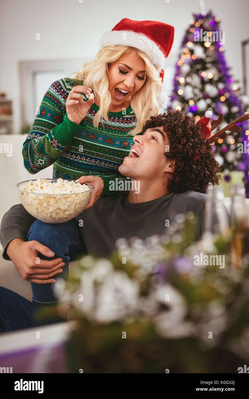 Paar in der gemütlichen warmen Pullover auf einem Weihnachten Silvester, lächelnd und Spaß miteinander essen Popcorn. Selektive konzentrieren. Stockfoto