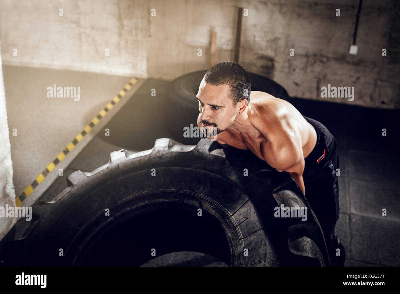 Junge muskulöse Mann Umdrehen eines Reifens auf Kreuz fit Training im Fitnessstudio. Stockfoto
