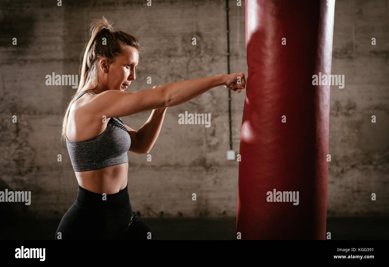 Junge muskulöse Frau Stanzen ein Boxsack auf Cross fit Training im Fitnessstudio. Stockfoto