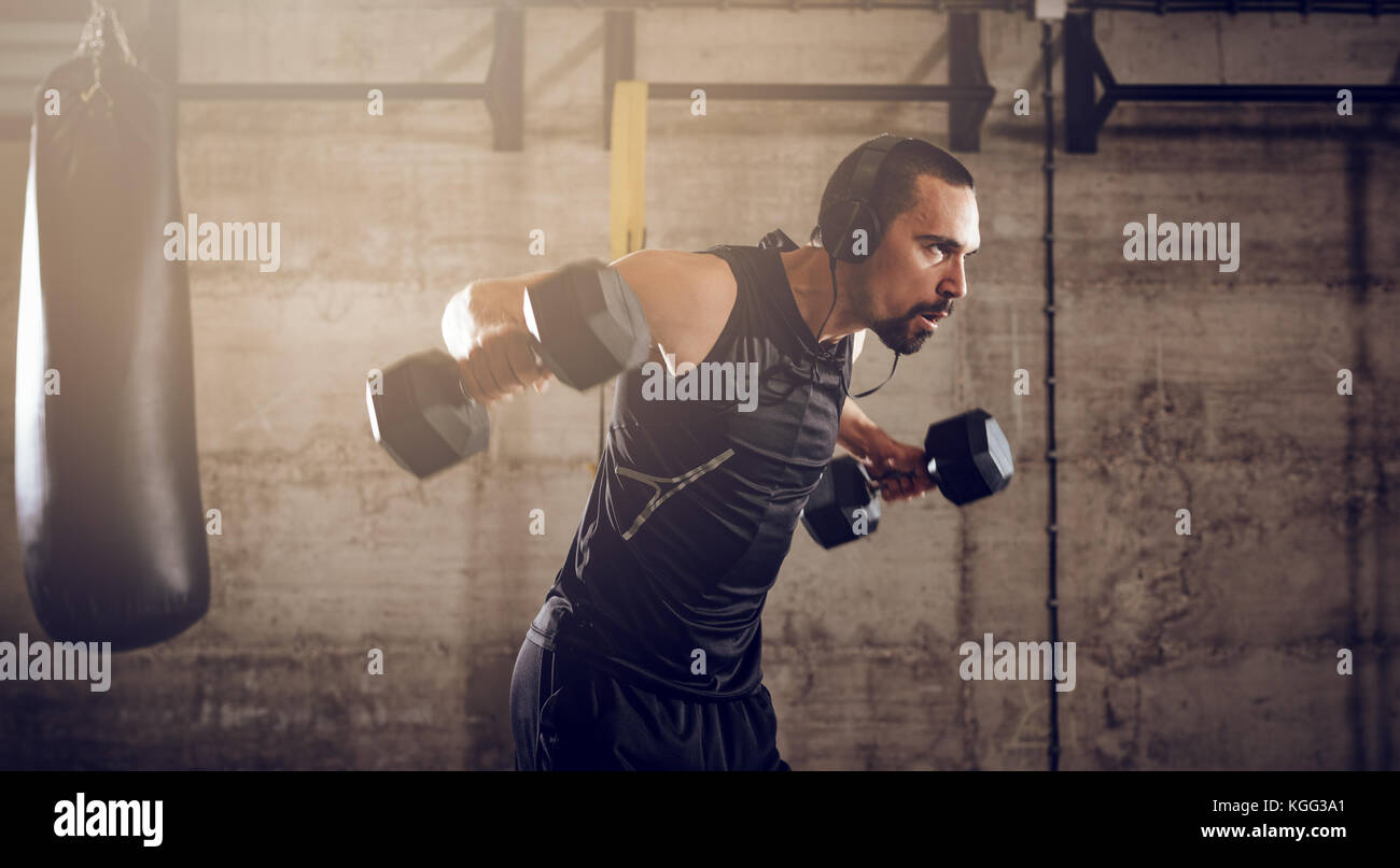 Junge muskulöse Mann Hard Training mit Hanteln für Schultern auf Kreuz fit Training im Fitnessstudio. Stockfoto