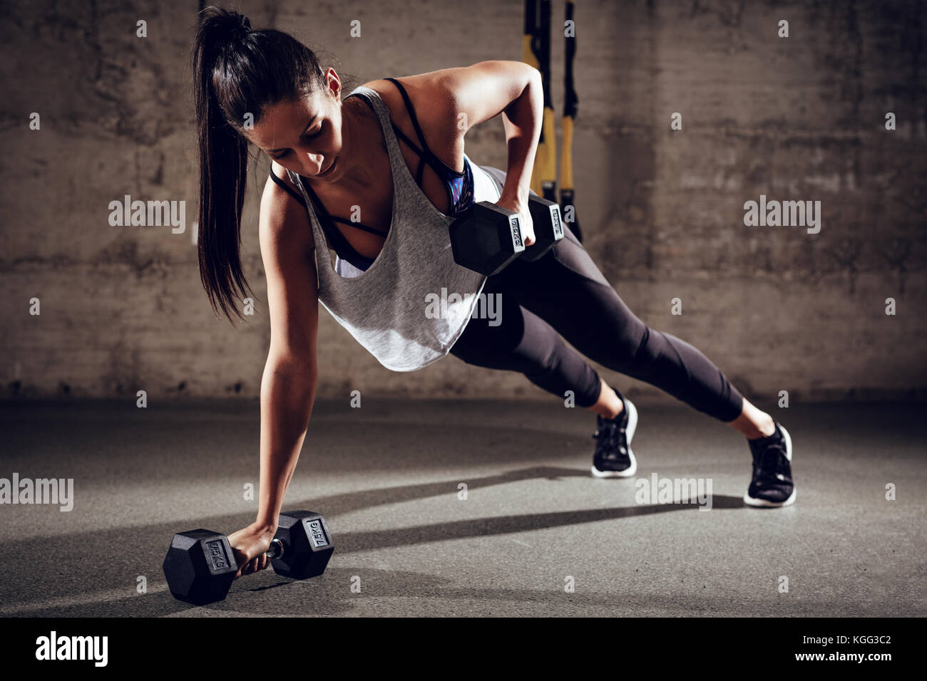 Junge muskulöse Frau tun plank Übung mit kurzhantelstange an der Turnhalle. Stockfoto
