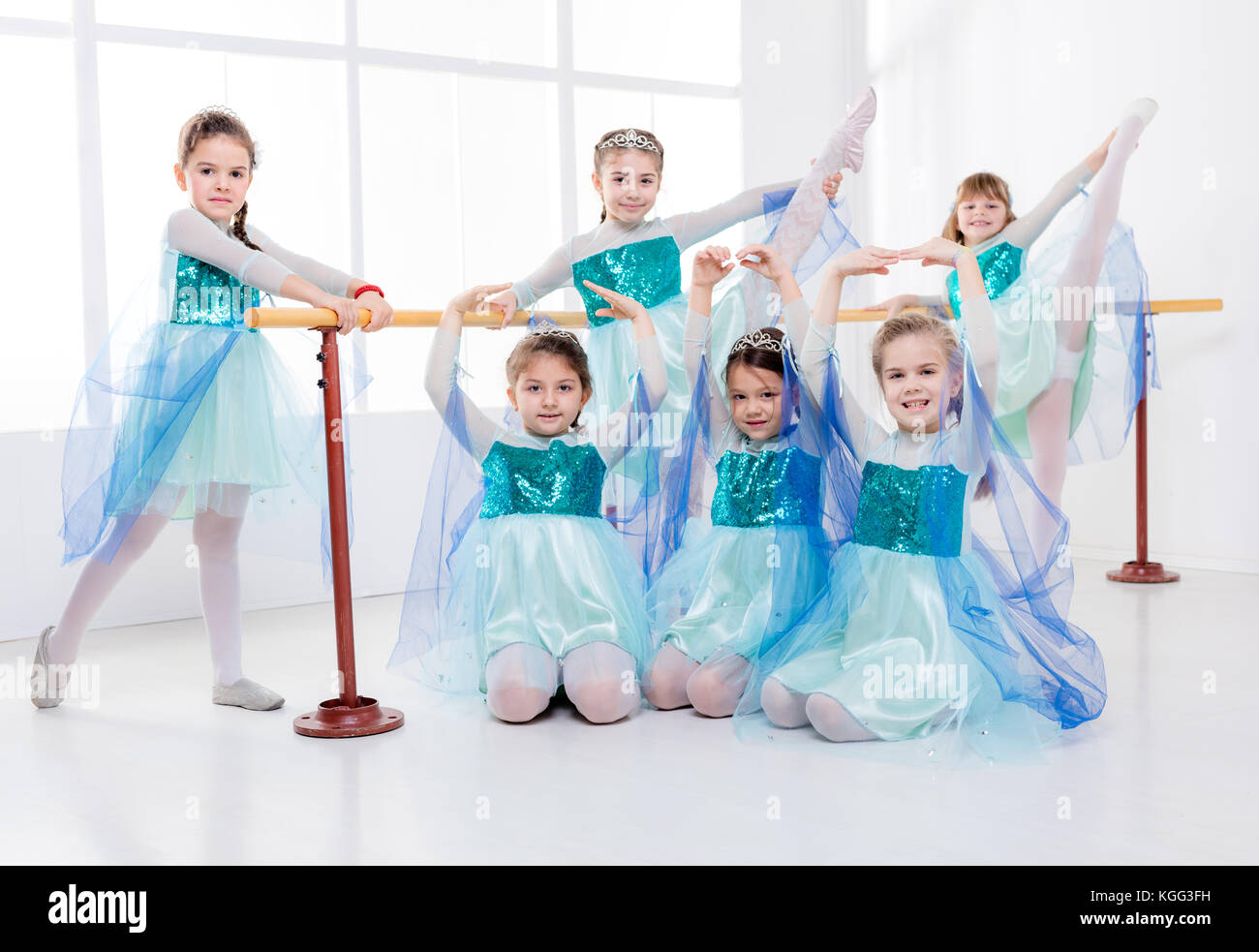 Lächelnde Mädchen in den Kleidern Üben von Haltungen während der ballettklasse. Bei Kamera schaut. Stockfoto