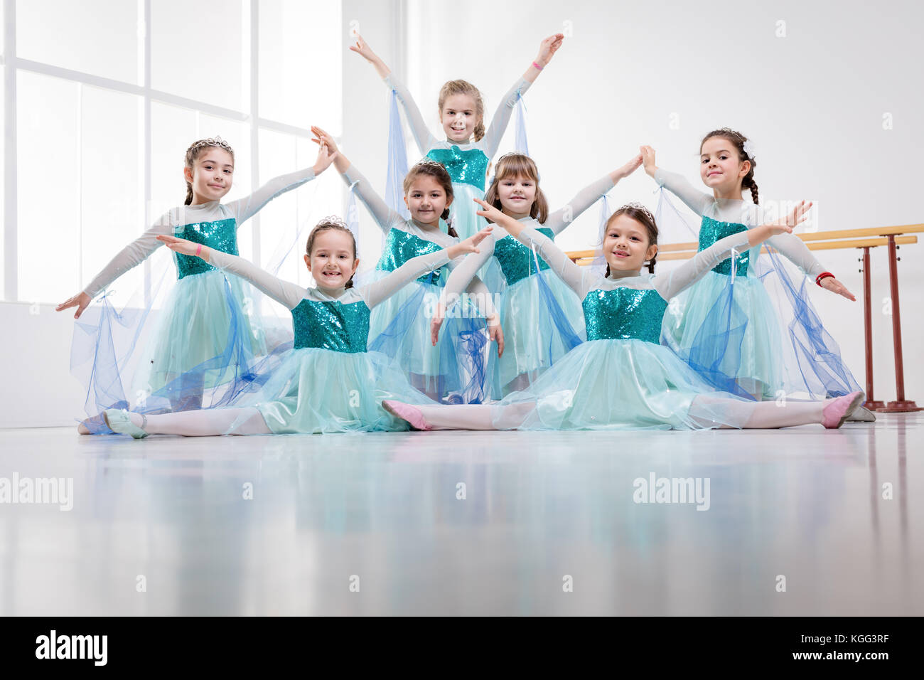 Lächelnde Mädchen in den Kleidern Üben von Haltungen während der ballettklasse. Bei Kamera schaut. Stockfoto