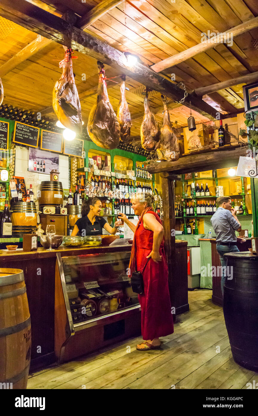 Eine Frau in einem roten Kleid bestellen Wein in La Antigua Abaceria Tapas-Bar, Calle Pureza, Triana, Sevilla, Andalusien, Spanien Stockfoto