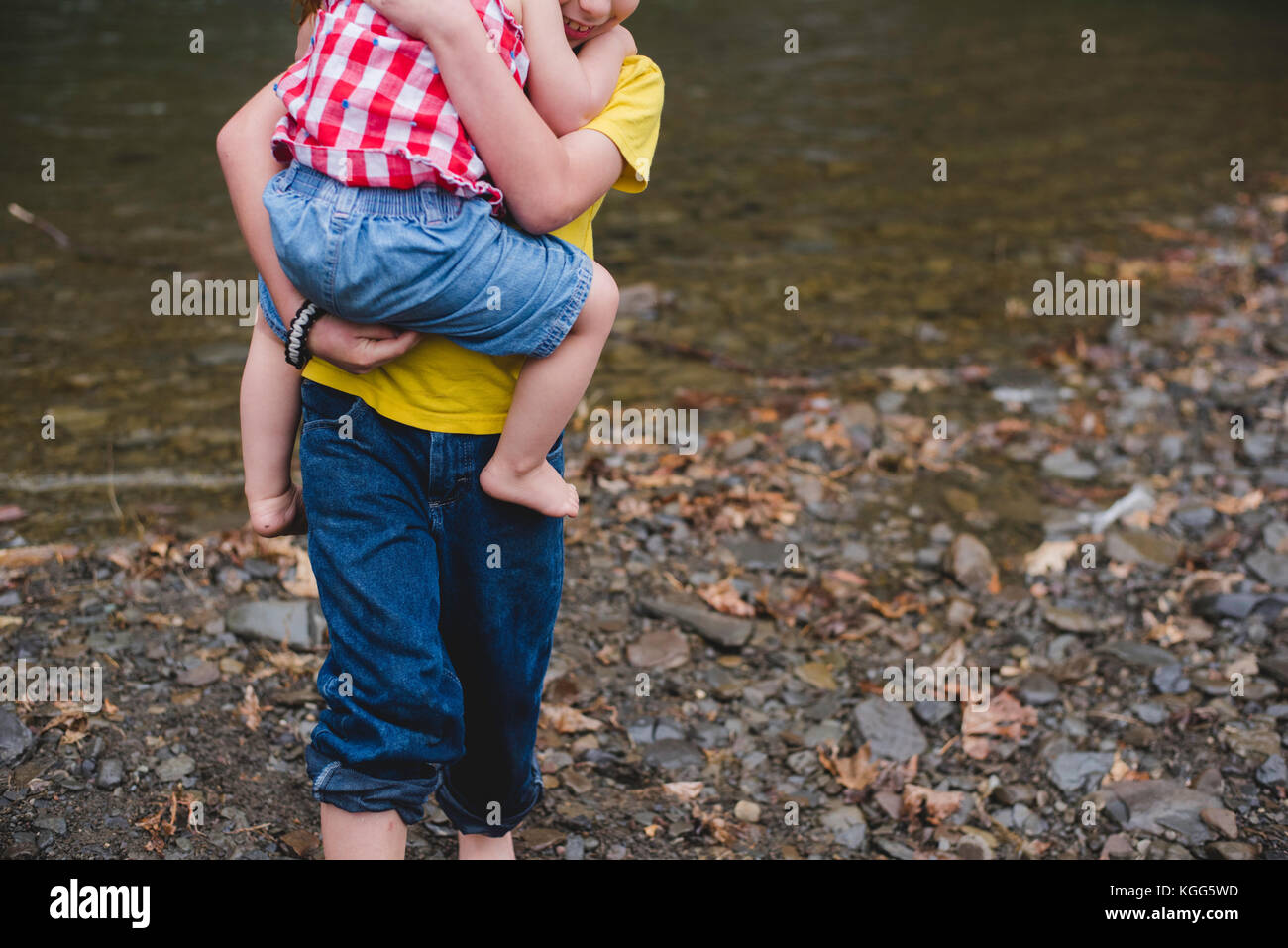 Ein Junge trägt ein Kind in seine Arme Stockfoto
