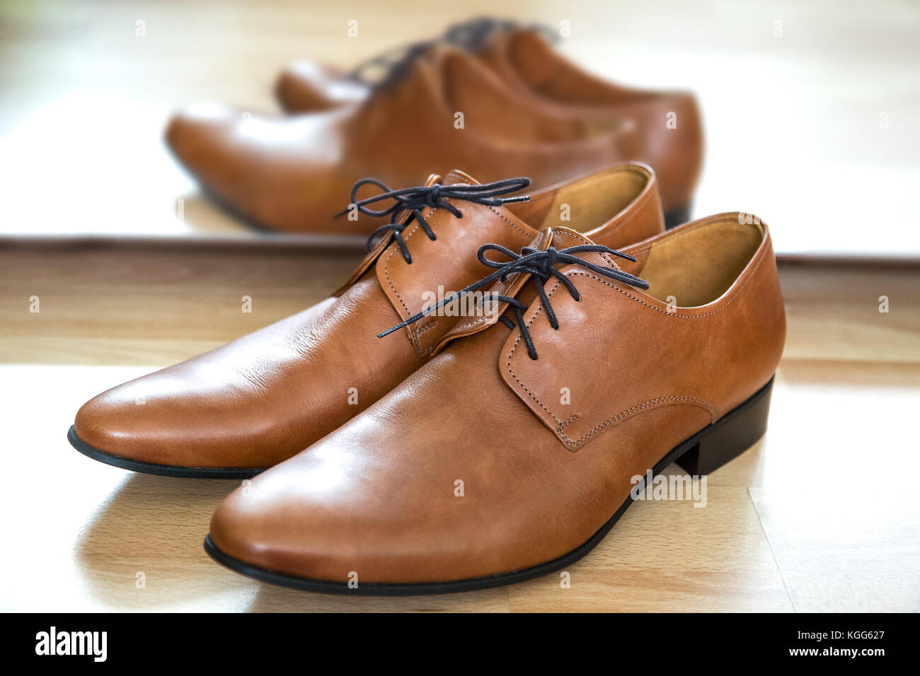Classic Brown Schnürschuhe aus Leder männliche Kleidung Schuhe neben dem Spiegel auf einem Holzboden. zeitlos Oxford Desing, glatte Toe, feine Nähte, Alle-le Stockfoto