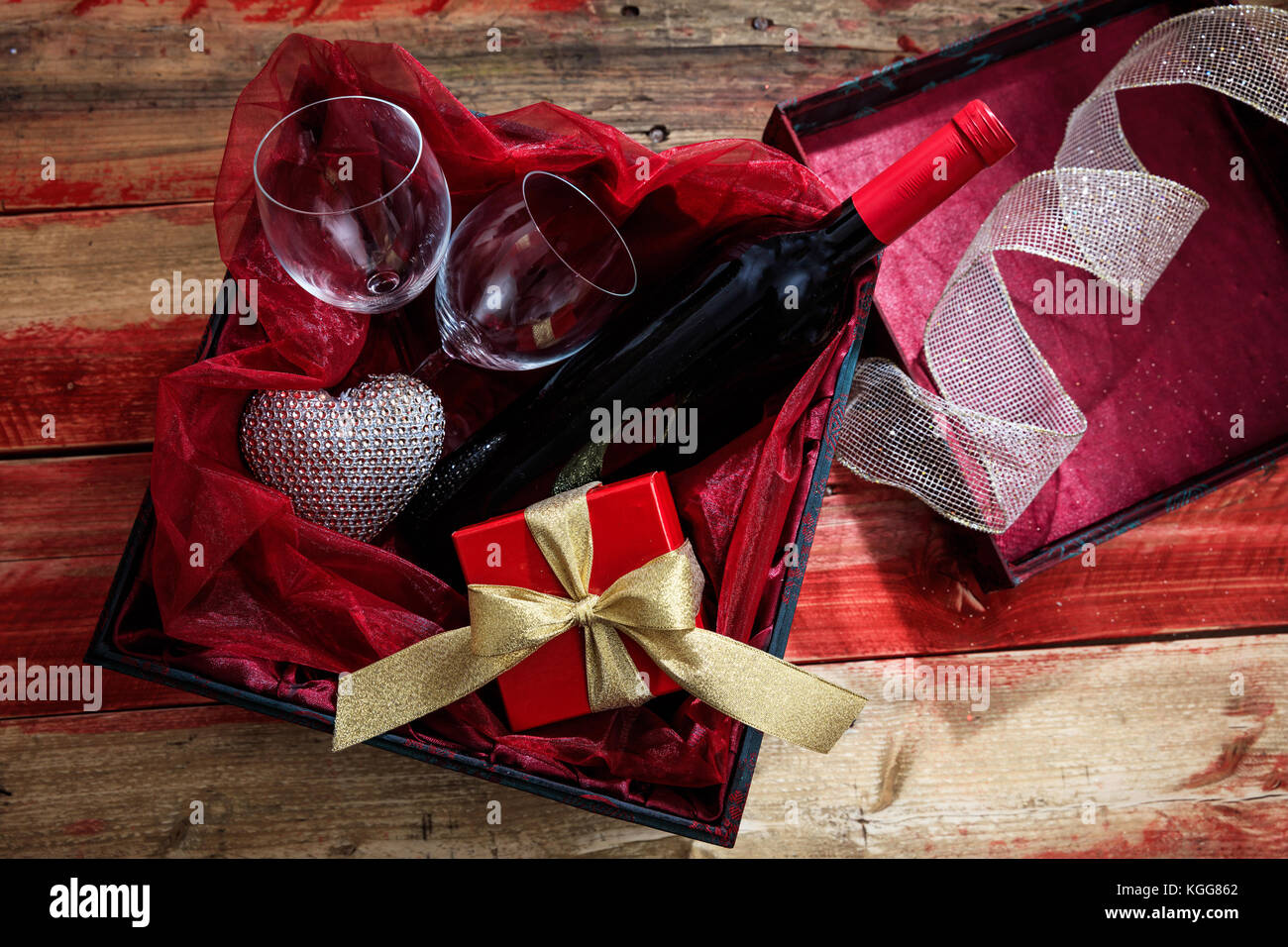 Valentines Tag Konzept. rote Flasche Wein, Gläser und ein Geschenk in einer Box, Holz- Hintergrund Stockfoto