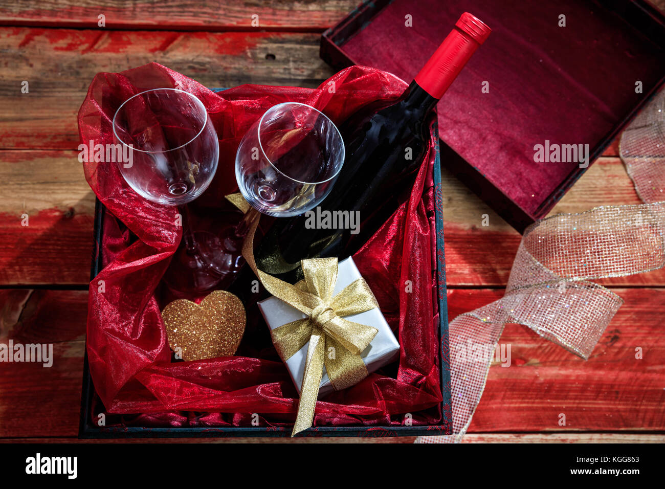 Valentines Tag Konzept. rote Flasche Wein, Gläser und ein Geschenk in einer Box, Holz- Hintergrund Stockfoto