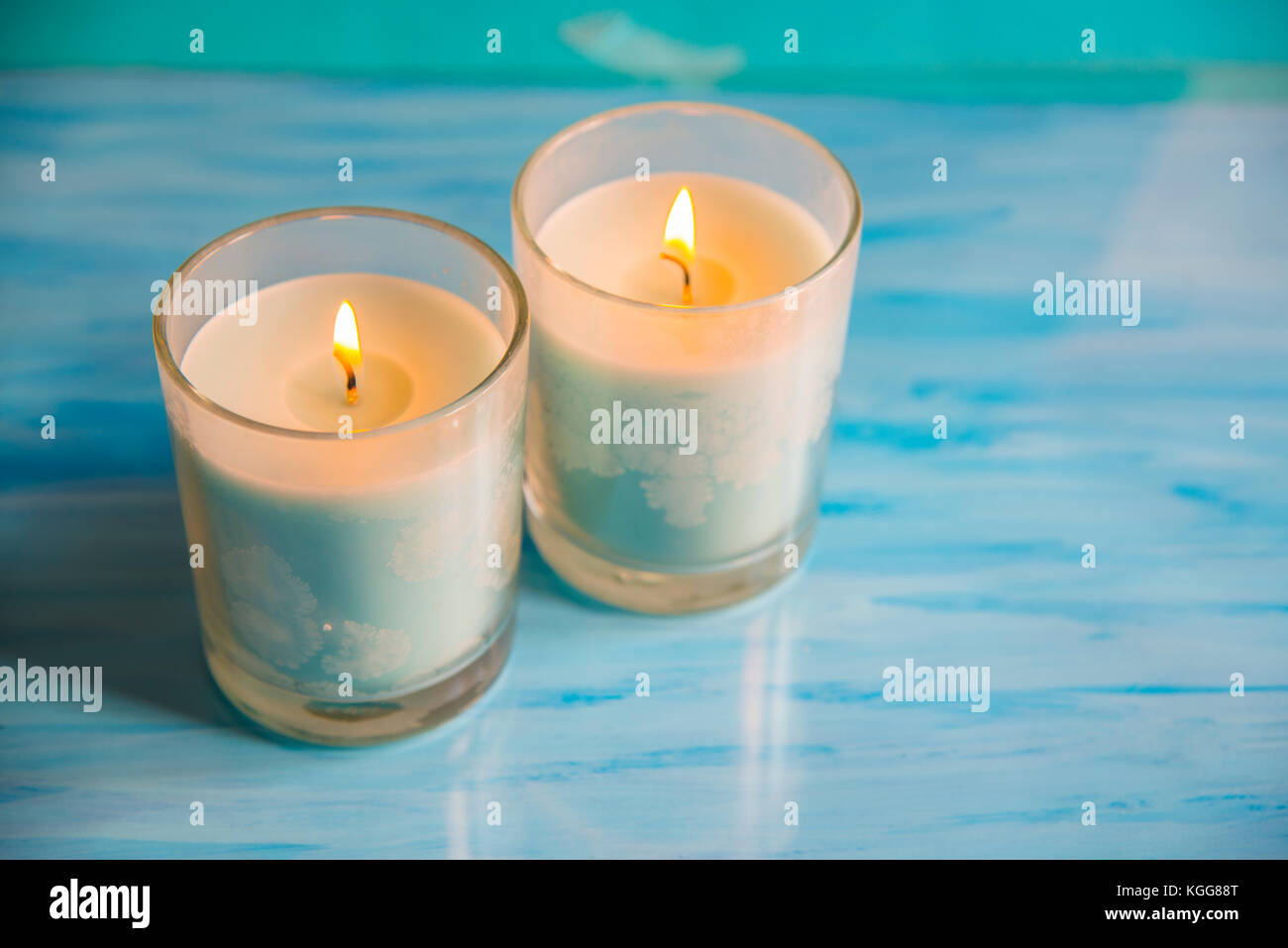 Zwei leuchten Kerzen auf blauen Fläche. Stockfoto