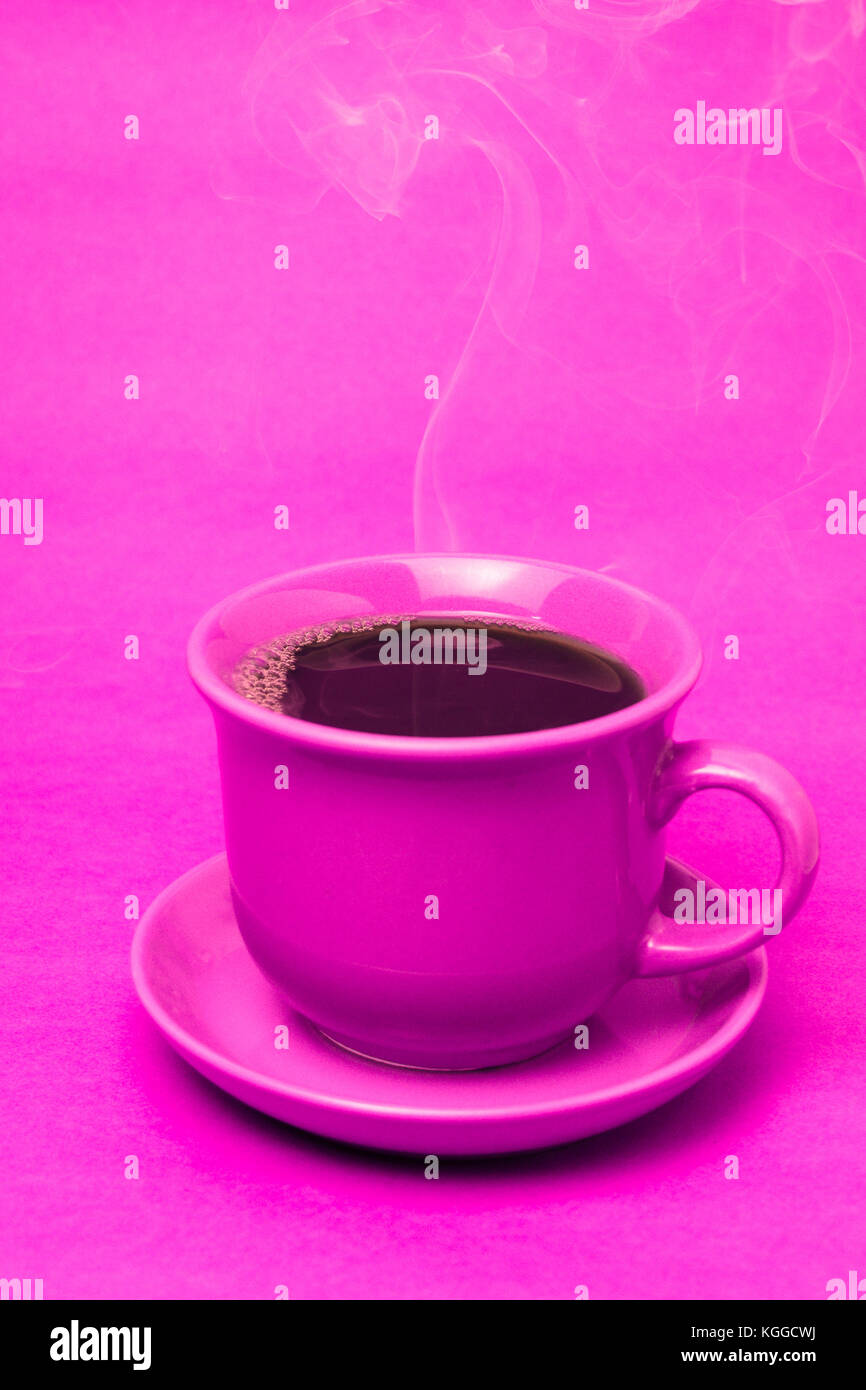 Rosa Tasse mit dampfenden heißen Kaffee. Weicher Rauch. Pinker Hintergrund. Vertikales Foto mit Platz zum Schreiben Stockfoto