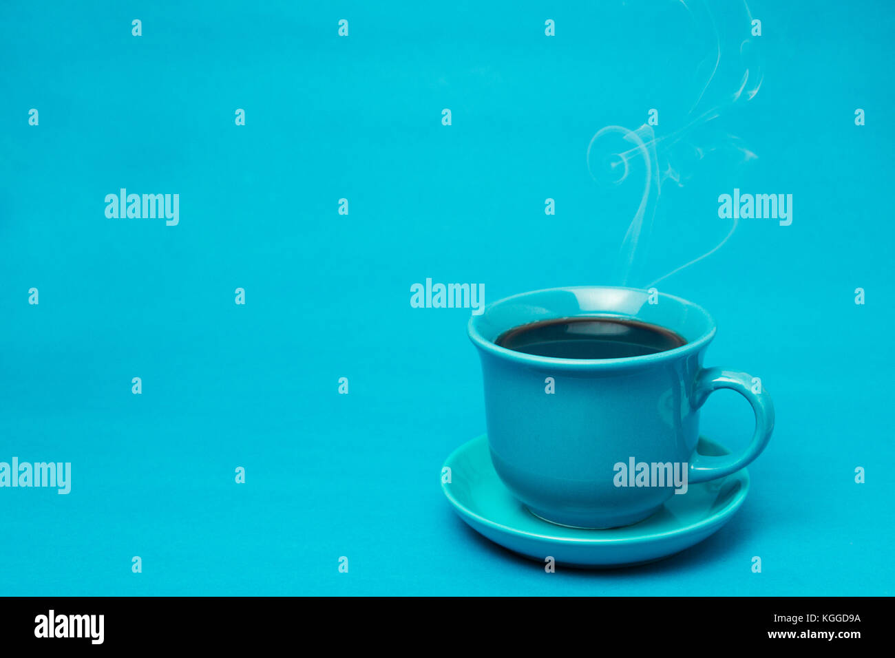 Blauer Becher mit dampfendem heißem Kaffee. Weicher Rauch. Blauer Hintergrund. Horizontales Foto mit Platz zum Schreiben Stockfoto